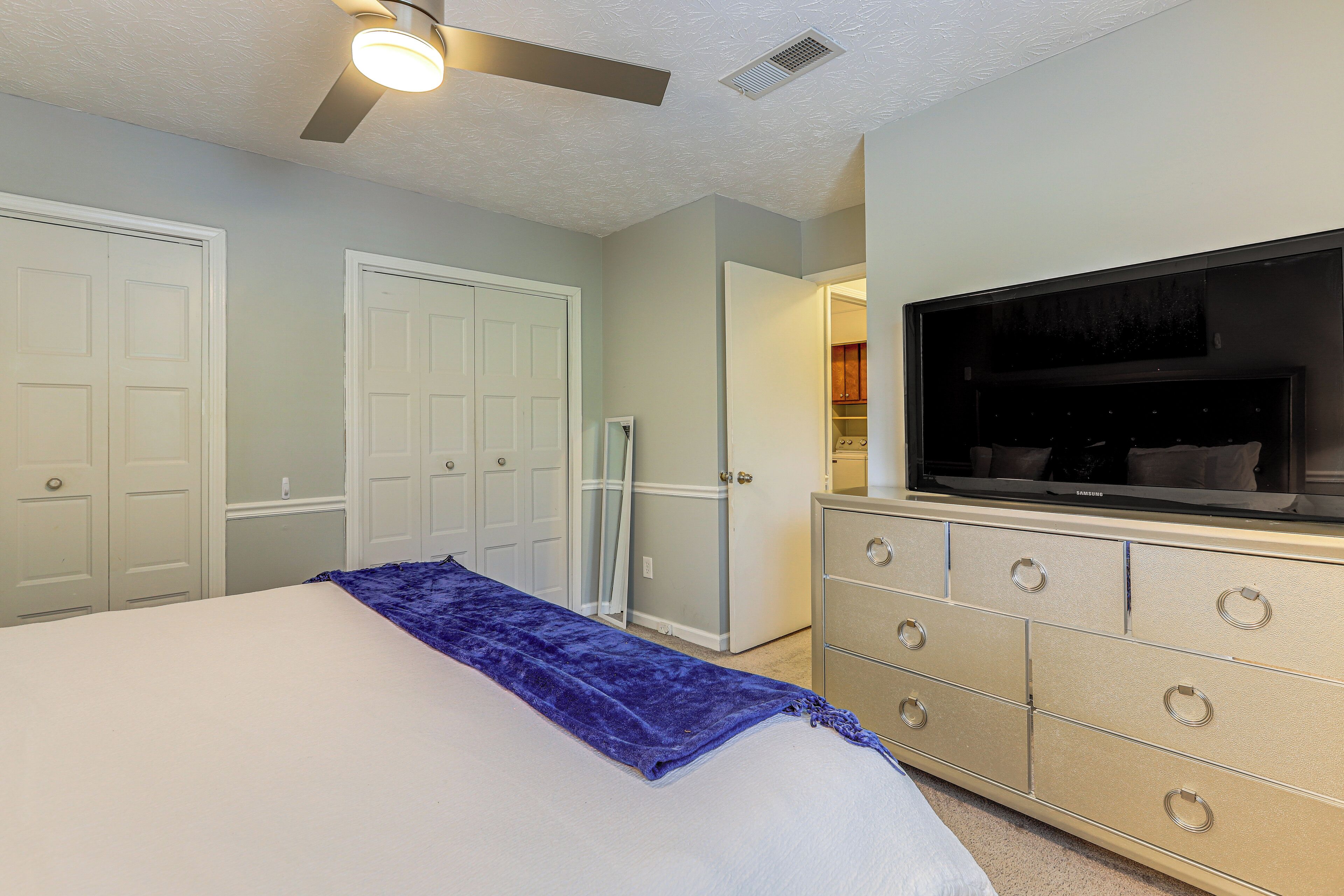 Een slaapkamer met een bed, een dressoir, een televisie en een kast.