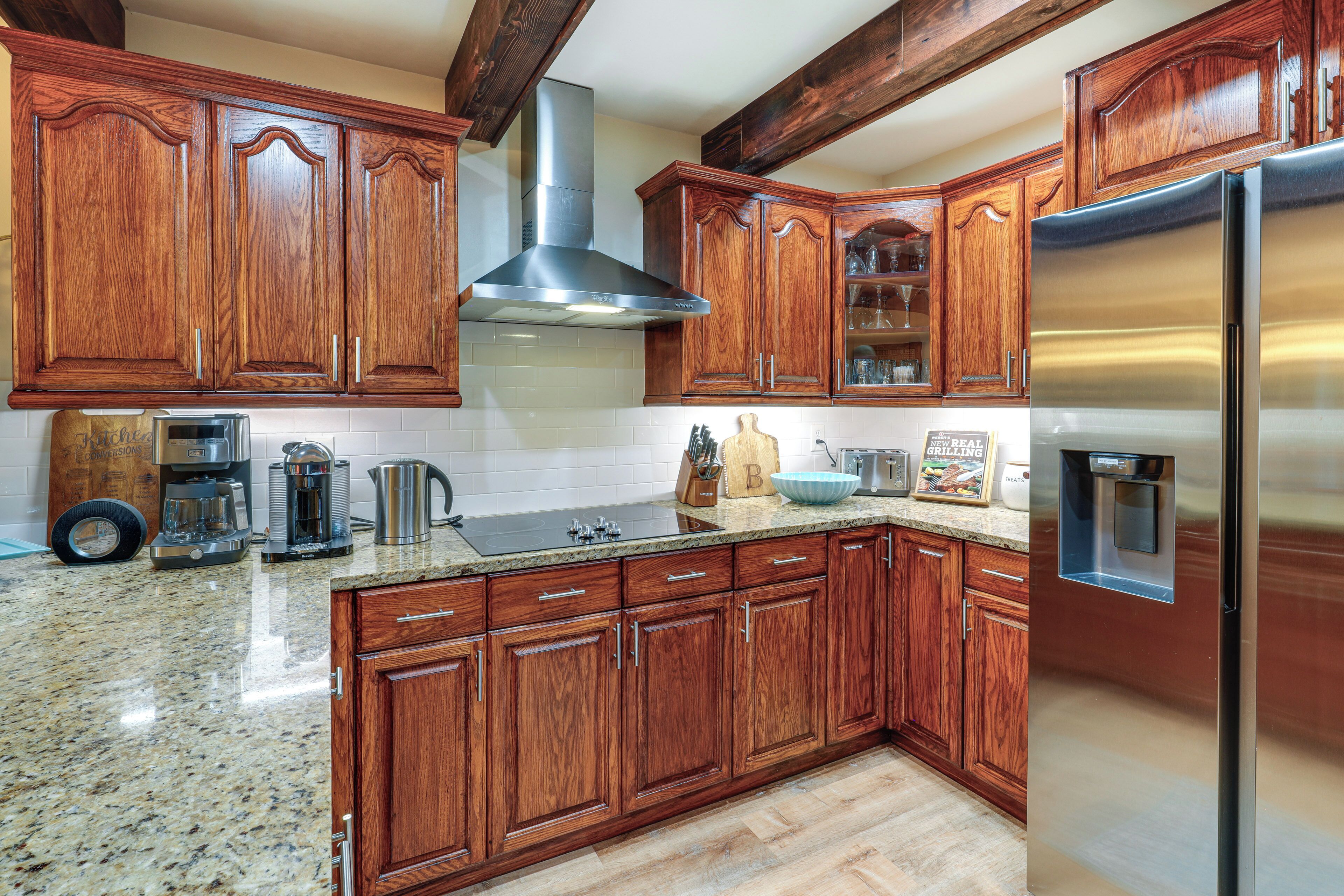 A kitchen with wooden cabinets, a stainless steel range hood, granite countertops, and a built-in refrigerator.