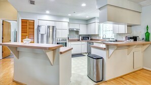 Una cocina moderna con armarios blancos, electrodomésticos de acero inoxidable y una isla central.