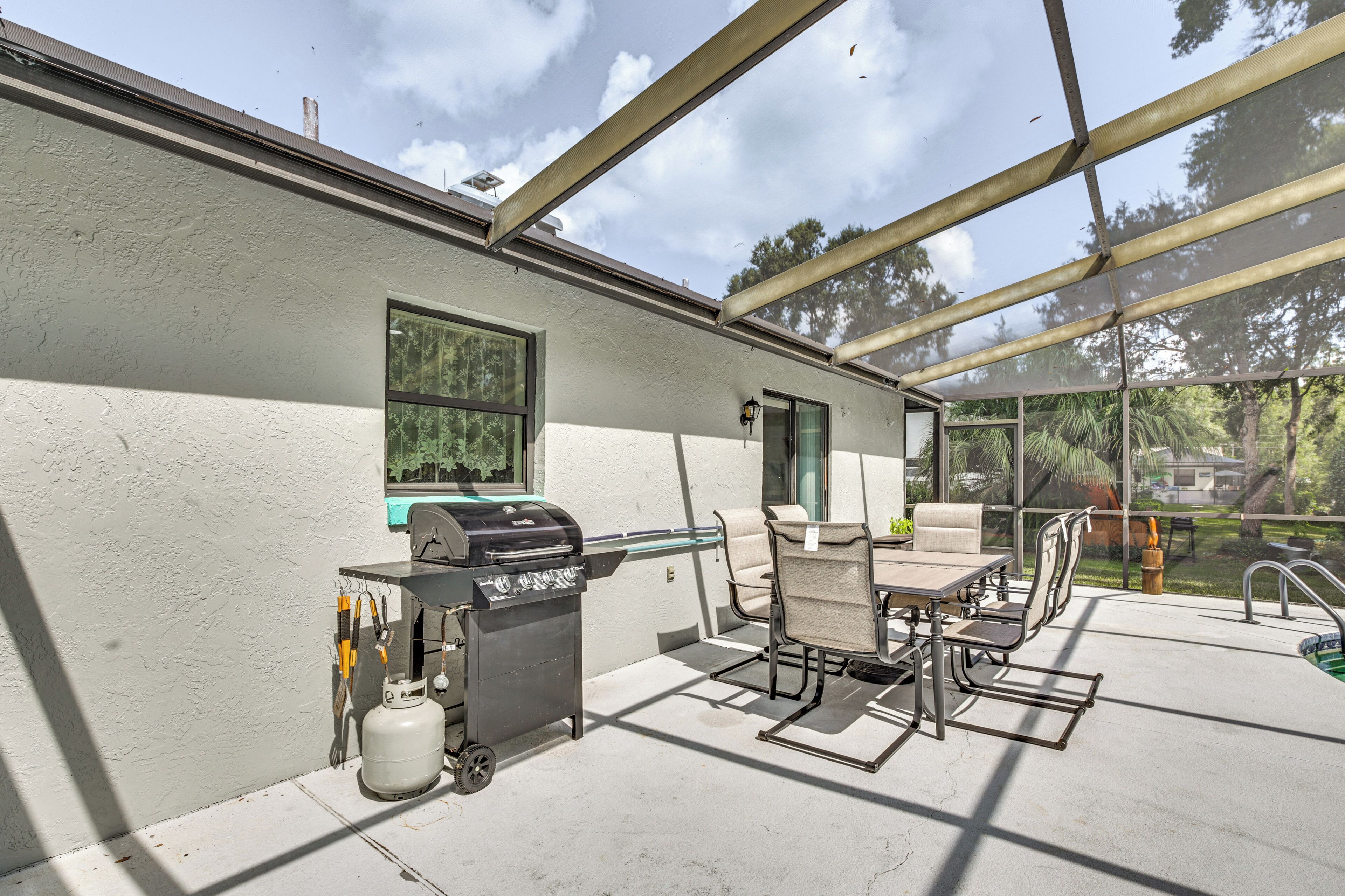 An outdoor patio with a grill, seating, and a view of the backyard.