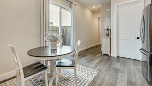 A modern kitchen with a stainless steel refrigerator, a dining table with chairs, and a patterned rug. - Fenced-in Yard: Apt 7 Mi to Westfield Galleria (Roseville)
