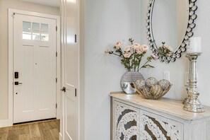 A hallway with a white door, a decorative mirror, a vase with flowers, and a silver candle holder. - Fenced-in Yard: Apt 7 Mi to Westfield Galleria (Roseville)