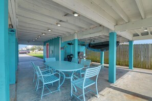 An outdoor patio with a round table and chairs, a grill, and a covered area with a blue fence. - Private Bayfront Access 10 Mi to Galveston Beaches (Hitchcock)