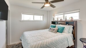 Ein Schlafzimmer mit Bett, Deckenventilator, Fenster und einem kleinen Tisch.