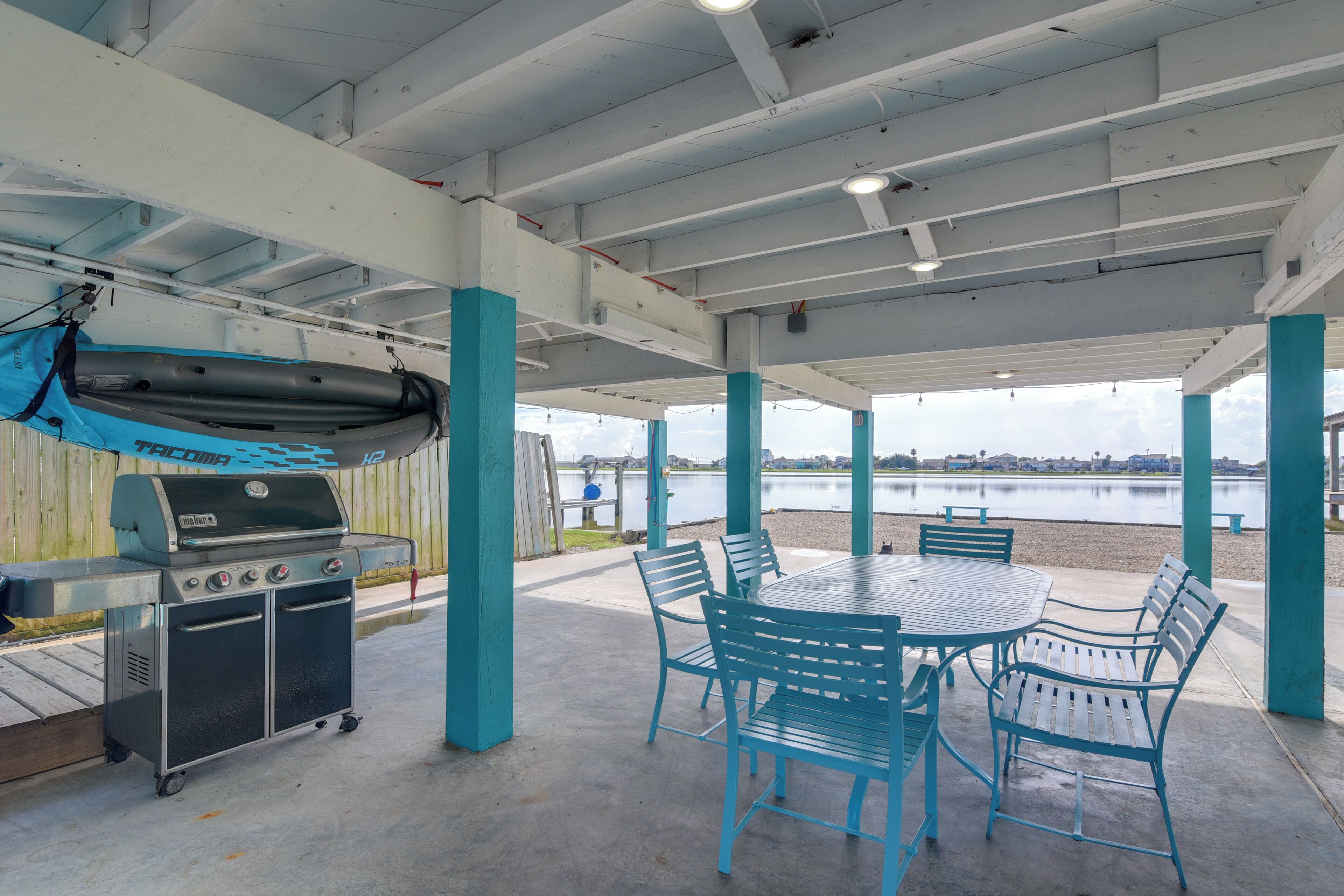 A covered outdoor area with a grill, seating, and a view of a body of water.