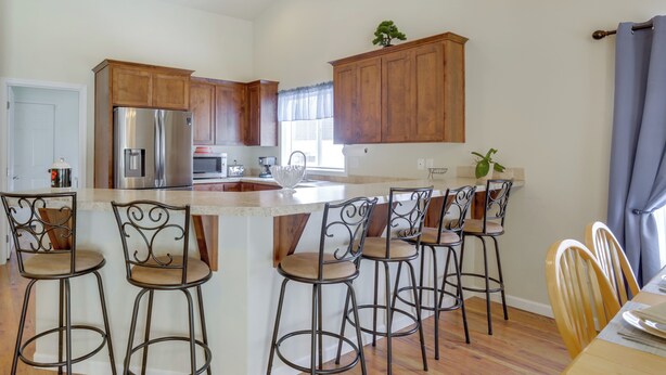 Une cuisine moderne avec des meubles en bois, des appareils en acier inoxydable et un îlot central doté de tabourets de bar.