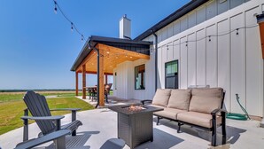 Eine Terrasse im Freien mit Adirondack-Stühlen, einer Couch und einer Feuerstelle.