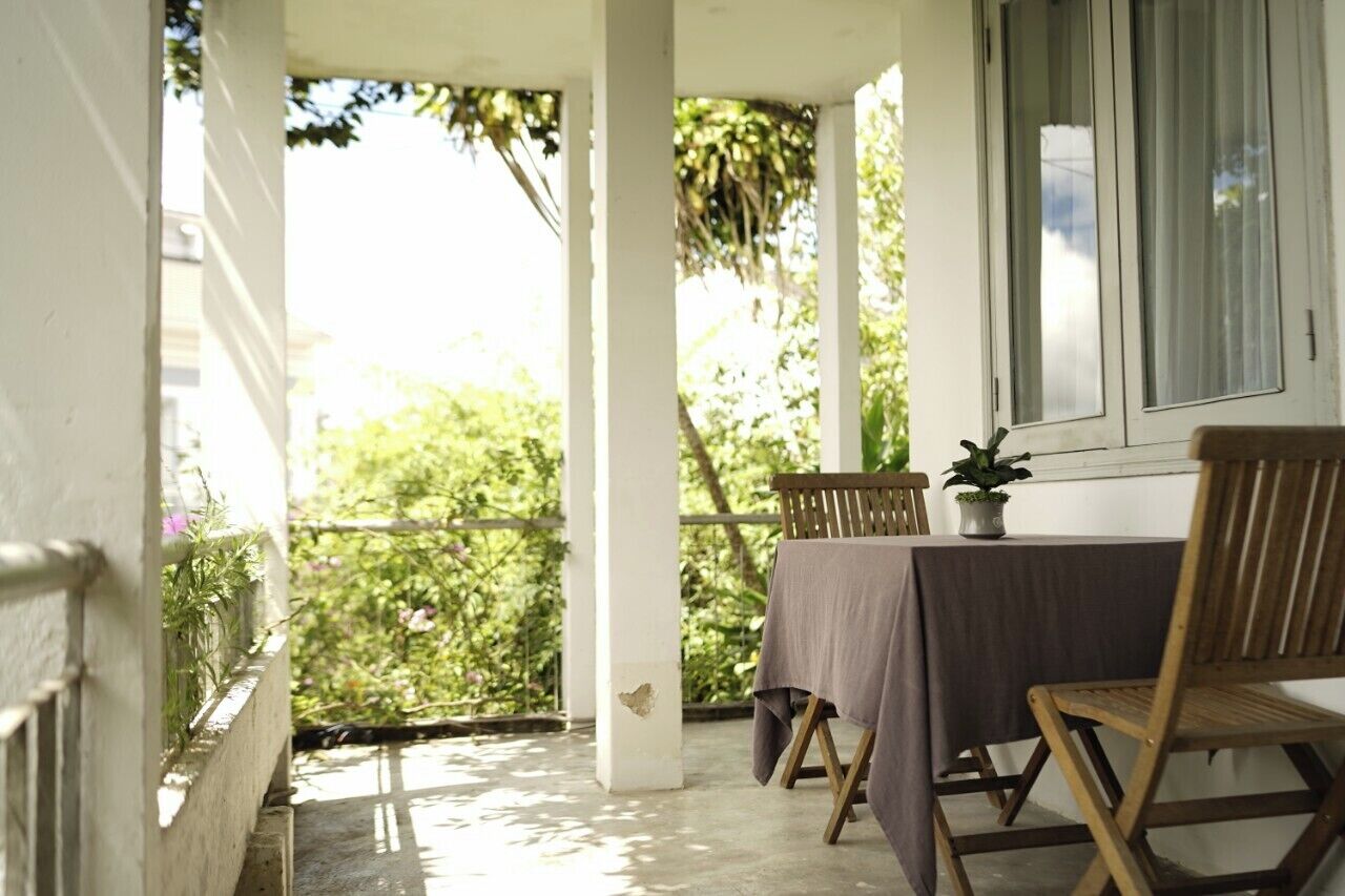 Un balcon avec une table et des chaises, une plante en pot et une vue sur la verdure.