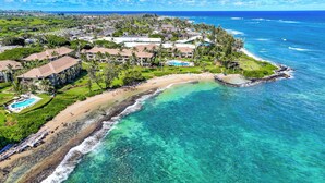 An aerial view of a coastal resort with multiple buildings, a beach, and clear turquoise waters.
