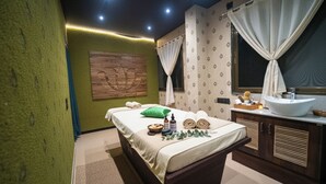 Een kamer met een bed, een groot raam met gordijnen, een wastafel en een houten paneel aan de wand.
