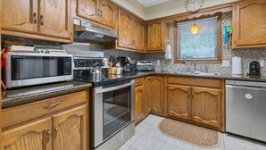 Una cocina con armarios de madera, microondas, estufa y lavavajillas.