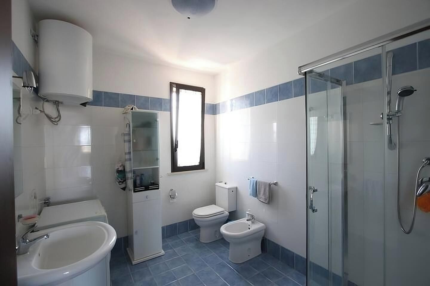Une salle de bain équipée d’une baignoire, de toilettes, d’un bidet et d’une douche à parois de verre.