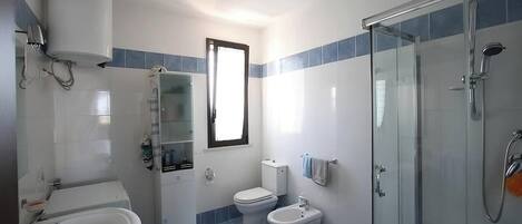 Une salle de bain équipée d’une baignoire, de toilettes, d’un bidet et d’une douche à parois de verre.