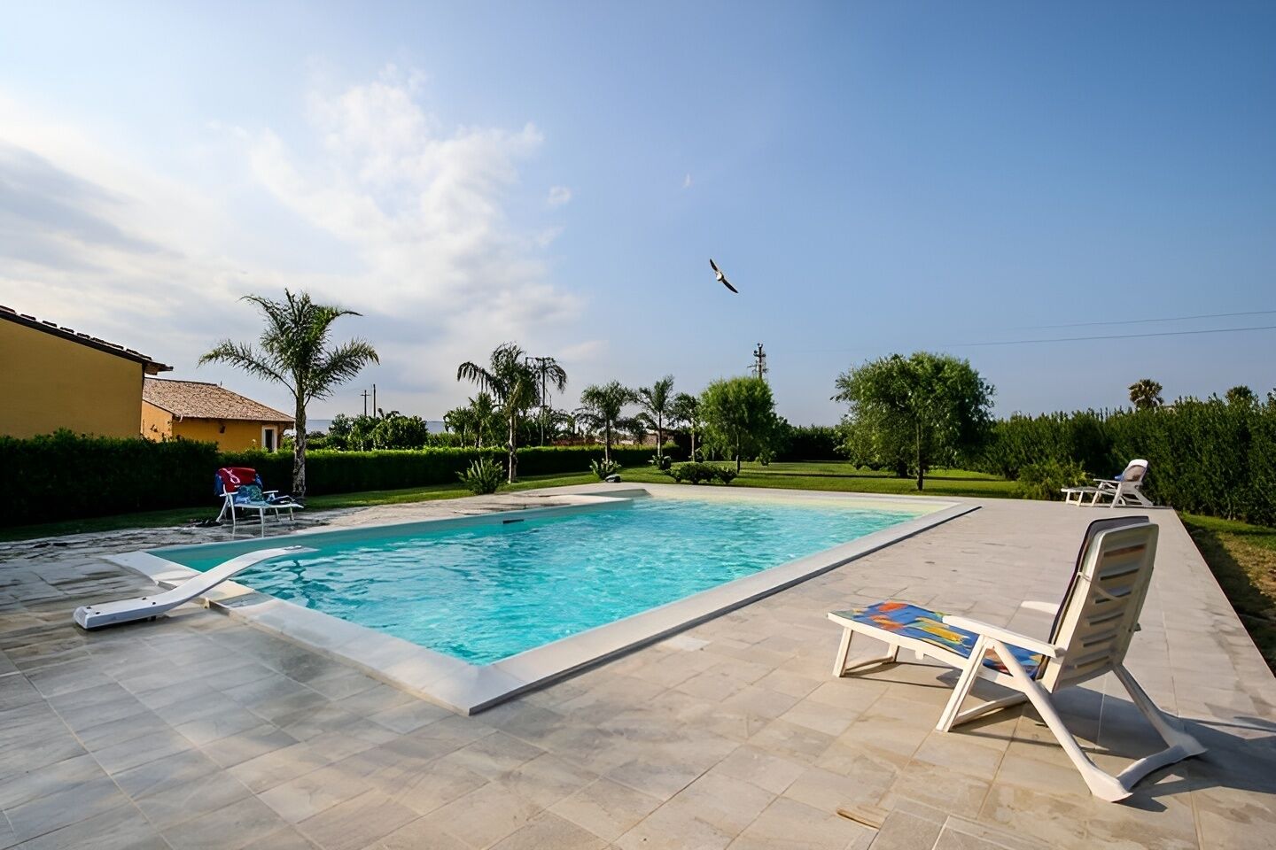 Une piscine avec des chaises longues et un ciel dégagé.