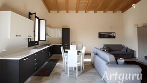 A modern kitchen with black cabinets, a white countertop, and a dining area with a gray sofa and white chairs. - House Lumia White Zagara (Sicilia)