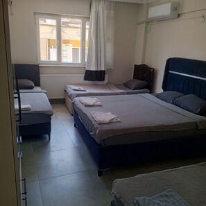 A hotel room with two beds, a window with curtains, a radiator, and an air conditioning unit. - anka suit (Aydın)
