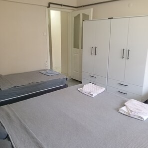A bedroom with two beds, a wardrobe, and a door leading to another room.
