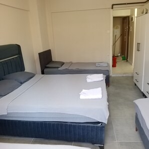 Et hotelværelse med to senge, et garderobeskab og et badeværelse i baggrunden.