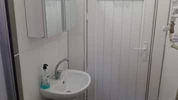 Apartamento estándar | Baño | Ducha, cabezal de ducha tipo lluvia, secador de pelo y zapatillas