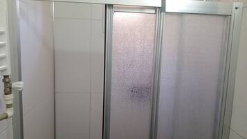 A shower enclosure with a frosted glass door, a metal handle, and a faucet.