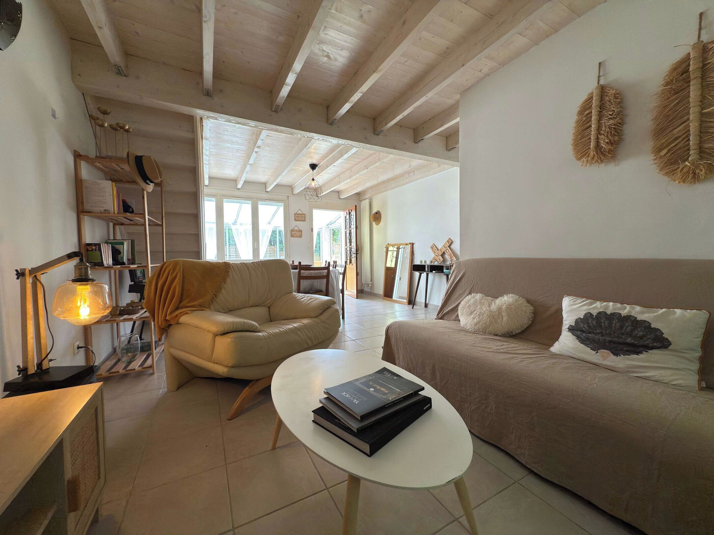 A spacious living room with a high ceiling, a sofa, a coffee table, and a bookshelf.
