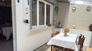 Un comedor con mesa y sillas, una ventana con vistas, y una pequeña cocina con refrigerador.