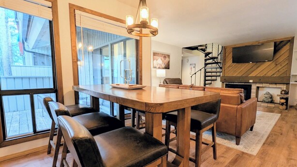 A modern kitchen with a wooden table and black leather chairs, a chandelier, and a fireplace. - Peaceful Retreat.  Outdoor Pool / Indoor Hot Tub (Keystone)