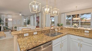 Una cocina moderna con encimeras de granito, electrodomésticos de acero inoxidable e iluminación colgante.