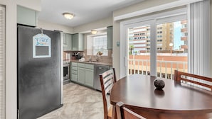 A kitchen with a refrigerator, cabinets, and a dining area with a table and chairs.