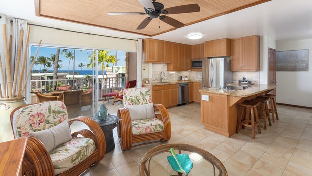 A spacious kitchen with wooden cabinets, a central island with stools, and a ceiling fan.