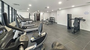Une salle de sport équipée de tapis de course, de vélos elliptiques et de matériel de musculation.