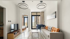 Un salon moderne avec un canapé, un téléviseur et un coin repas équipé de chaises.