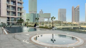 A rooftop pool area with a circular hot tub, surrounded by a low wall and palm trees. - FIRST CLASS | 1BR |  Waterfront Bliss (Al Maryah Island)
