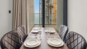 A dining table set for four with a view of a construction site through large windows. - FIRST CLASS | 1BR |  Waterfront Bliss (Al Maryah Island)