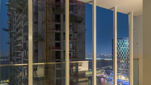 A high-rise building with a construction site visible through large floor-to-ceiling windows. - FIRST CLASS | 1BR |  Waterfront Bliss (Al Maryah Island)