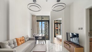 A modern living room with a sofa, dining table, and TV. - FIRST CLASS | 1BR |  Waterfront Bliss (Al Maryah Island)