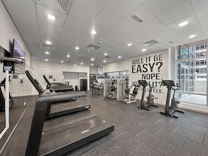 A gym with treadmills, weight machines, and a motivational quote on the wall.