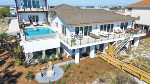 Une maison moderne à deux étages dotée d’une piscine, d’un espace salon extérieur et d’une terrasse couverte.