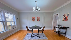 A dining area with a round table, two chairs, a chandelier, and artwork on the walls. - Charming 1BR Apt in Evanston (Evanston)