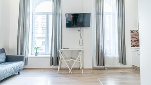 A modern living room with a sofa, a TV mounted on the wall, and a small table.