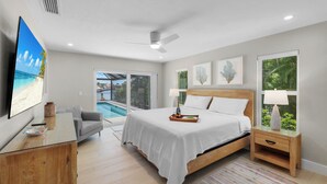 A bedroom with a bed, bedside table, TV, and a view of a pool. - Canal home w/ pool, kayak, foosball, and ping pong (Marco Island)