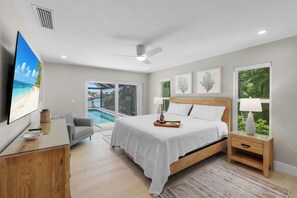Un dormitorio con cama, mesita de noche, televisor y vistas a una piscina.