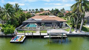 A house with a swimming pool, dock with kayaks, and palm trees. - Canal home w/ pool, kayak, foosball, and ping pong (Marco Island)