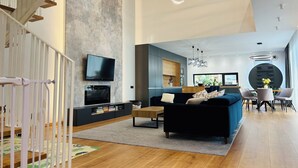 Una sala de estar moderna con un sofá negro, un televisor de pantalla plana y un comedor con dos sillas y una mesa.