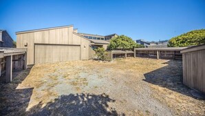 A modern building with a large garage door, surrounded by a gravel driveway and wooden fences.