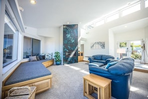 A modern living room with a large window, a blue sofa, and a built-in bench.