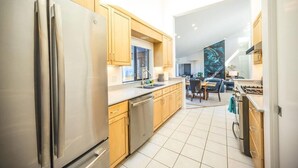 A modern kitchen with stainless steel appliances, wooden cabinets, and a dining area with a table and chairs.