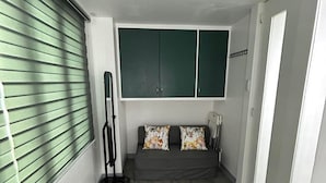 A room with a grey sofa, green cabinets, and a standing fan. - Simple but Cozy, Feel at Home (Mandaluyong)