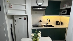 A compact kitchen with white cabinets, a microwave, a sink, and a clock above the stove. - Simple but Cozy, Feel at Home (Mandaluyong)