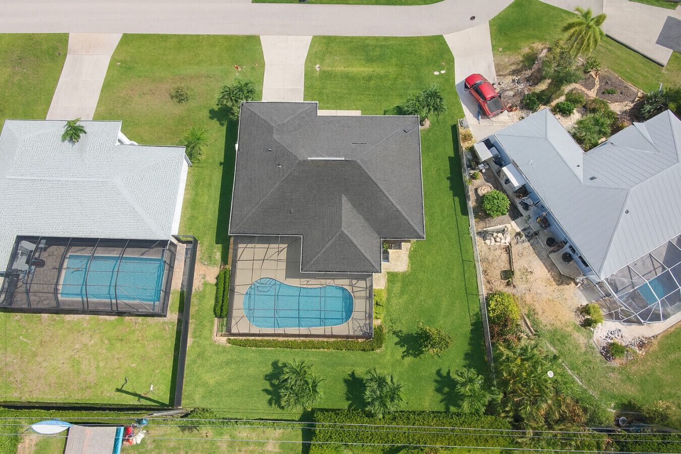 A residential property with a large swimming pool, multiple garages, and a well-maintained lawn.